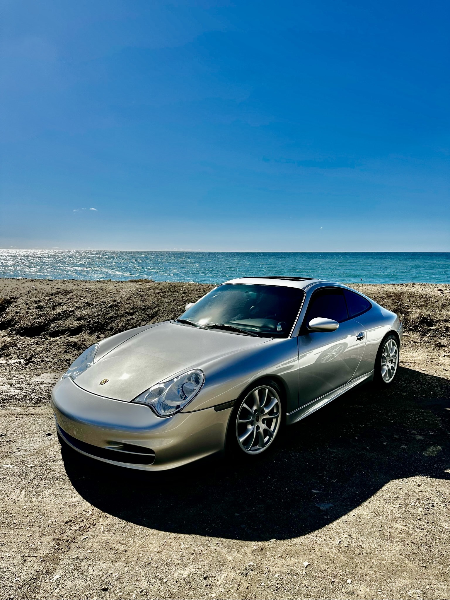 A 996 Carrera parked on a mountain pass - the open door reveals the tan leather interior.